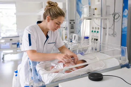 Neonatologieverpleegkundige verzorgt een pasgeborene in de couveuse