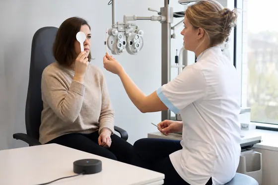 Orthoptist voert een oogmeting uit bij een cliënt in de onderzoekskamer