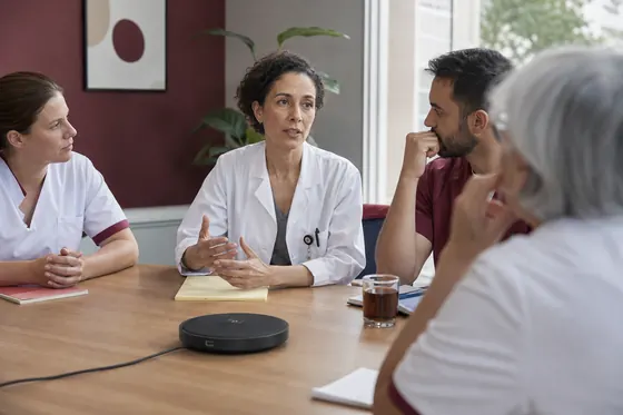 Specialist ouderengeneeskunde in multidisciplinair overleg met collega's aan een tafel