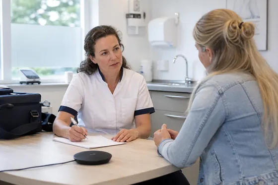 Praktijkverpleegkundige bespreekt gezondheidsvragen met een cliënt